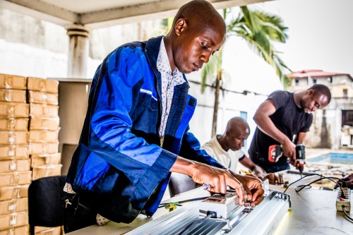 Technicus Maxime is bezig met de montage van de aansluiting voor een LED-straatlamp. Op de achtergrond zijn twee collega's Jérôme en Eyral. CAC-CI-04